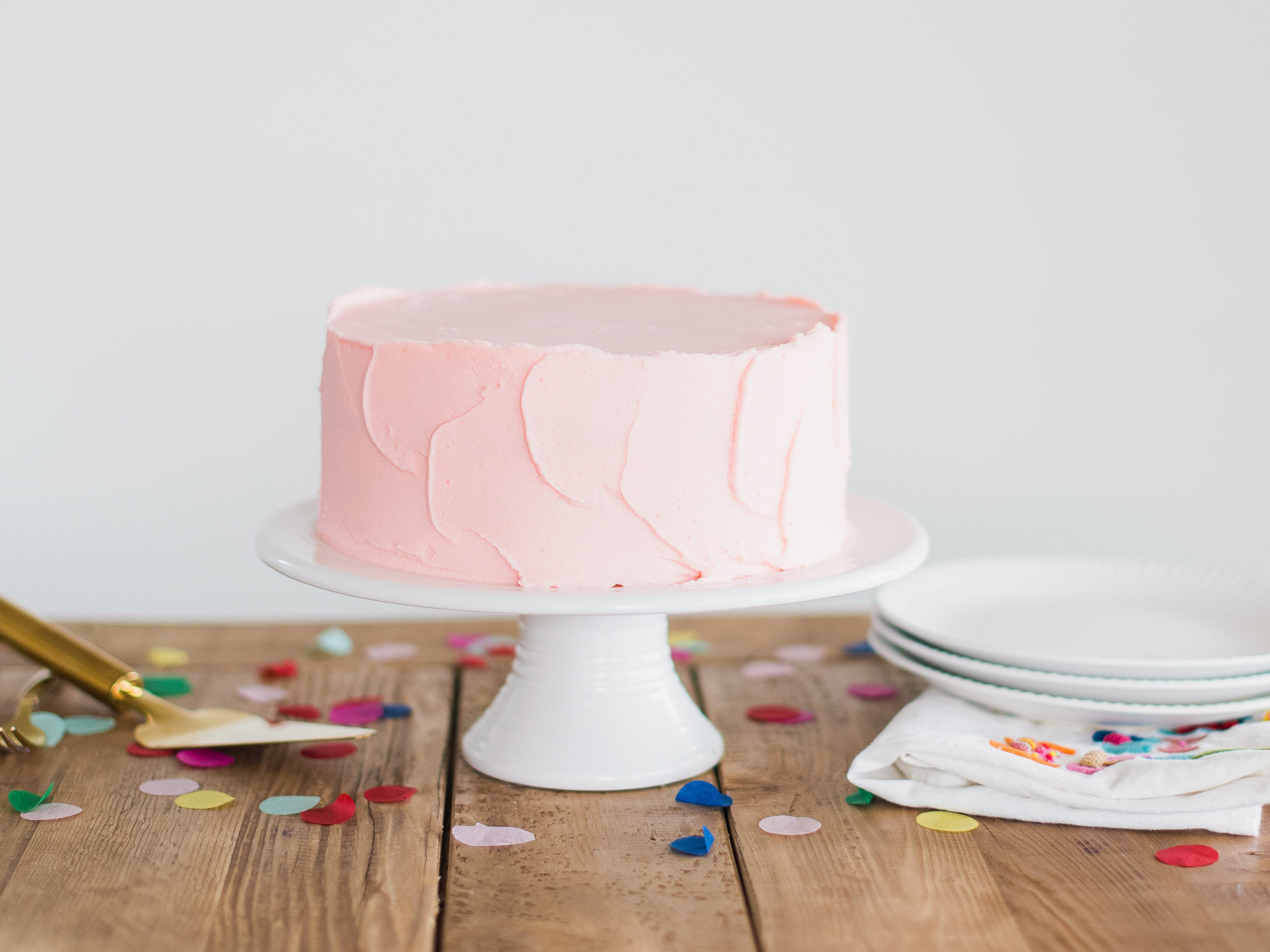 A pink frosted sugar free cake on a cake stand.