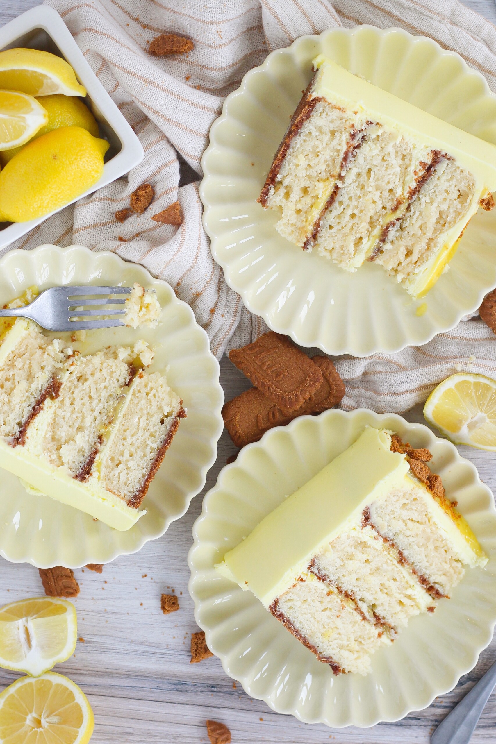 Three slices of cake on a table with plates and forks.