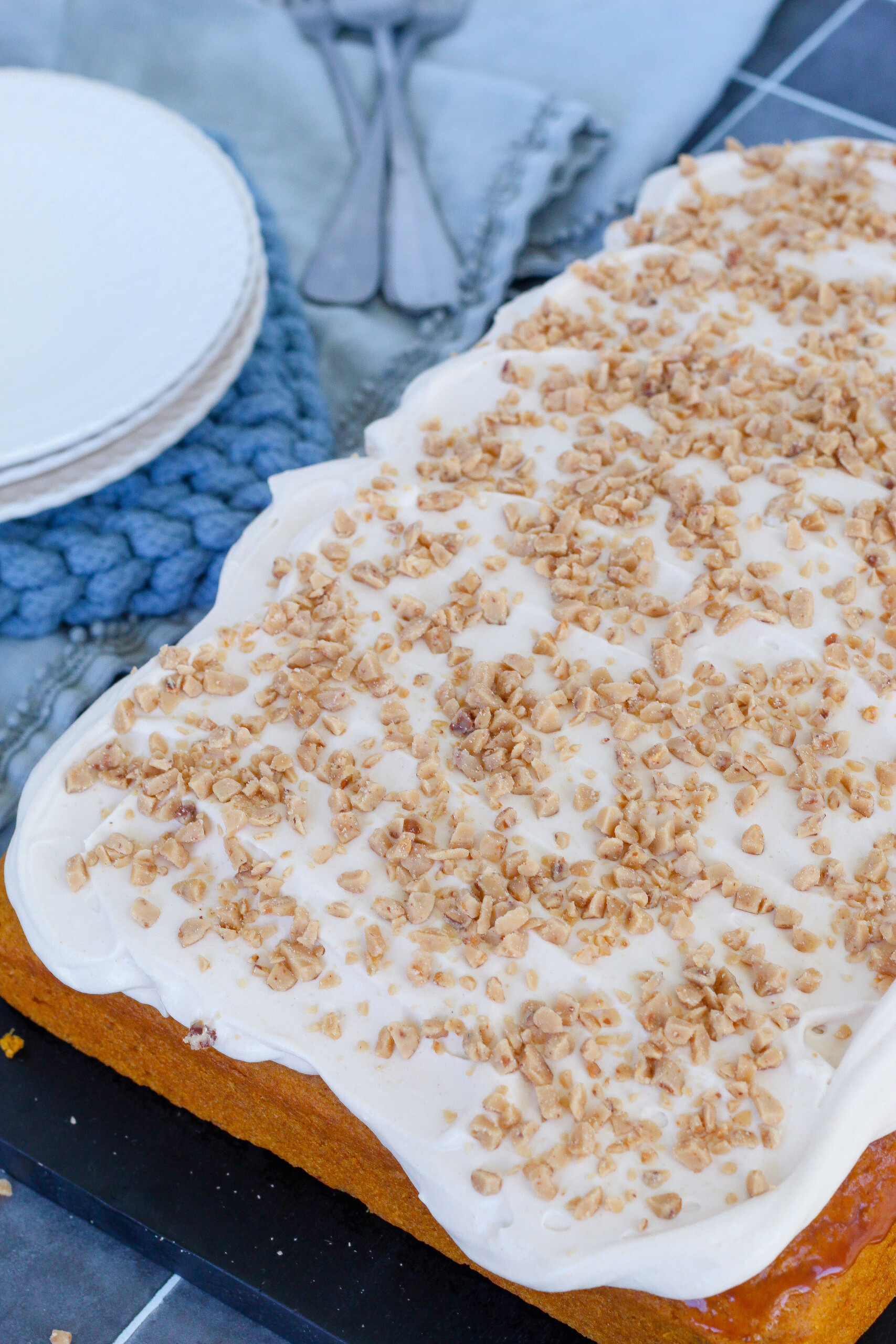 A pumpkin sheet cake on a cutting board with plates nearby.