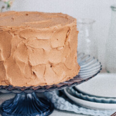 Banana cake with nutella buttercream on a cake stand with plates.