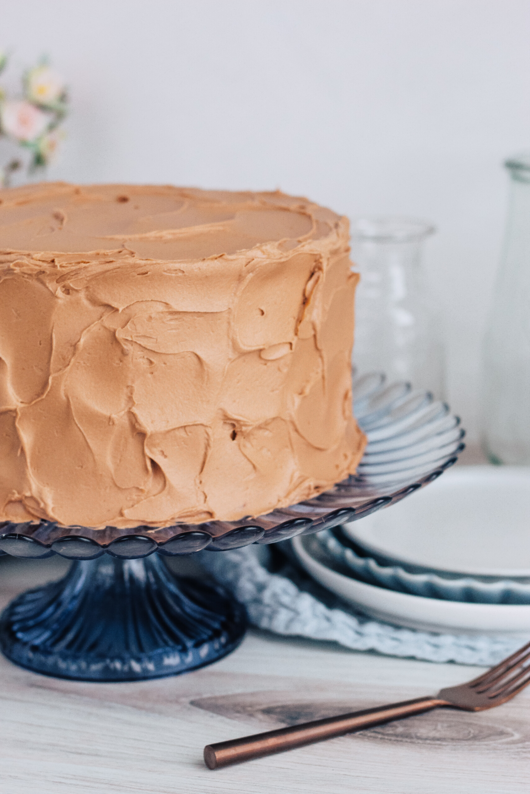 Banana cake with nutella buttercream on a cake stand with plates.