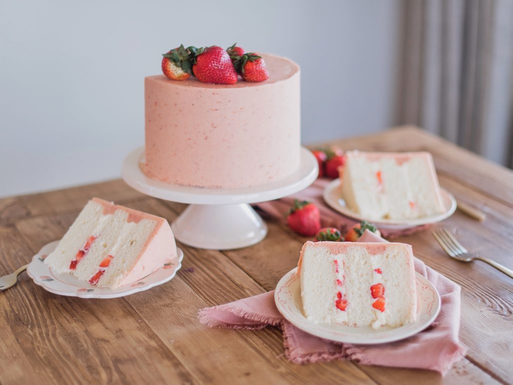 Strawberry Shortcake: Tender and fluffy layers of vanilla cake, filled with whipped cream and fresh strawberries, and covered in a strawberry buttercream. #cakebycourtney #cake #cakerecipe #strawberryshortcake #shortcake #strawberry #buttercream
