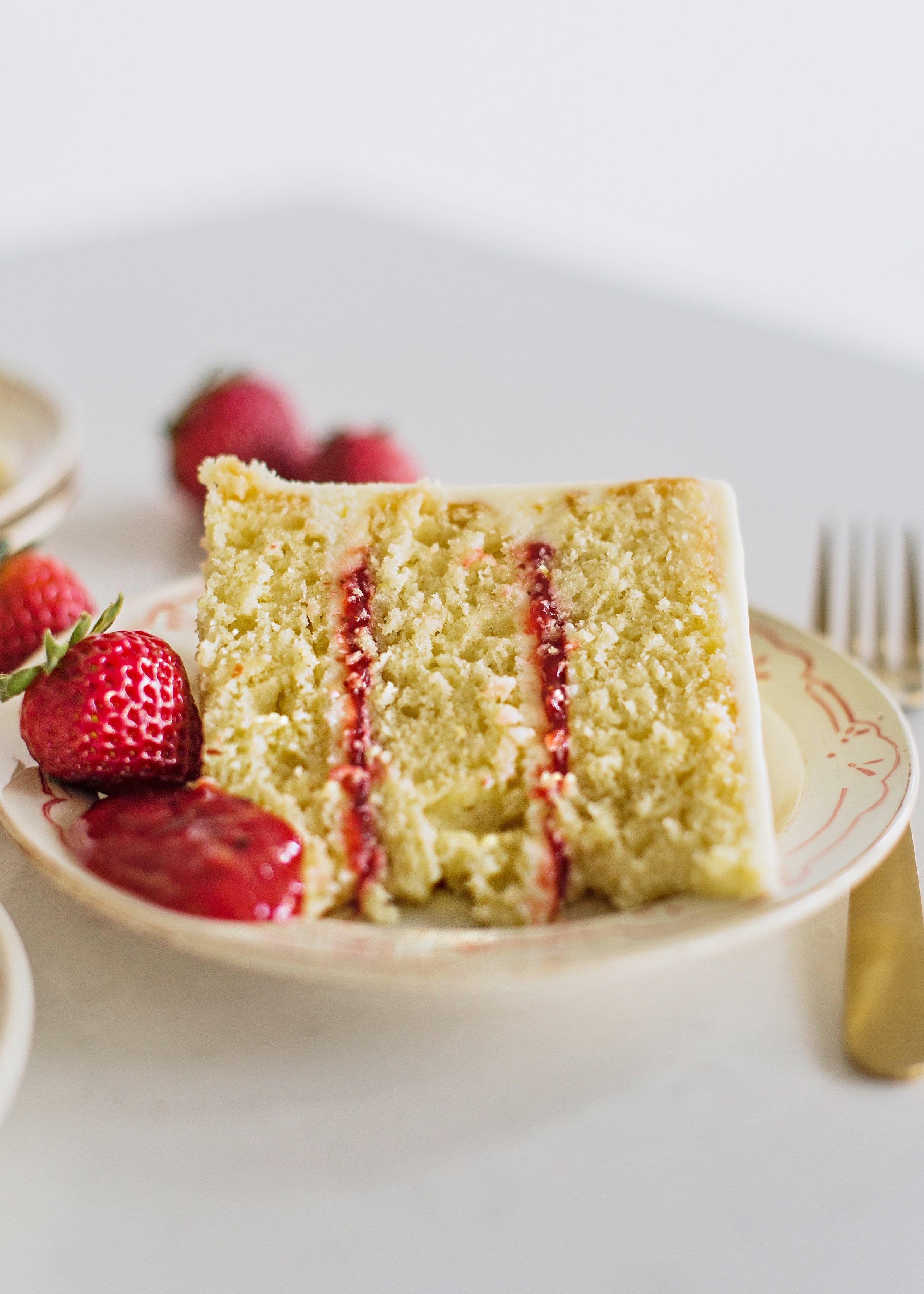 Slice of Olive Oil cake on a plate with strawberries.