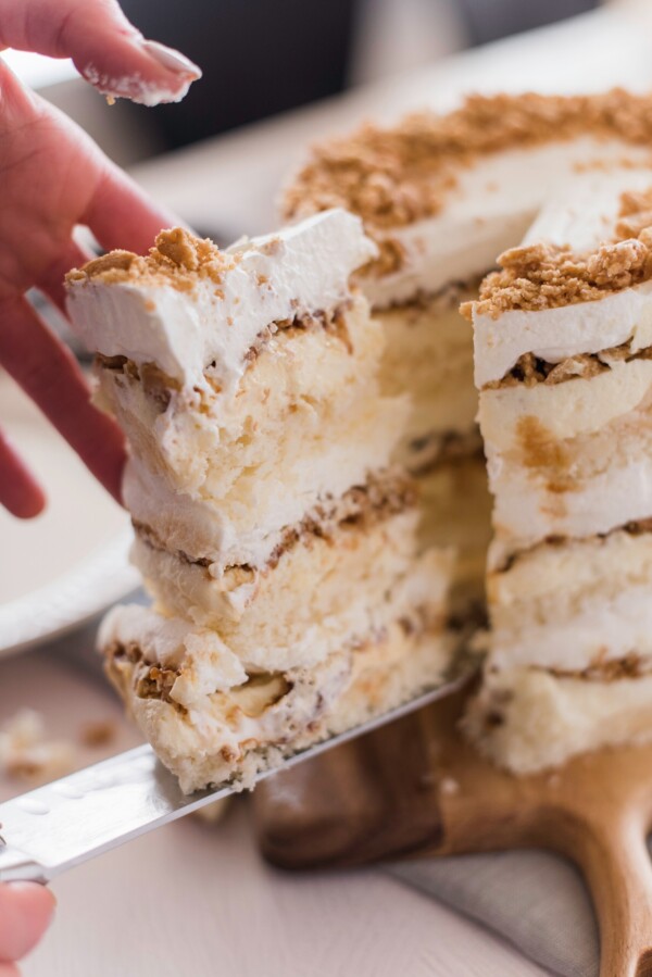 Person taking a slice of cake out of a whole cake.